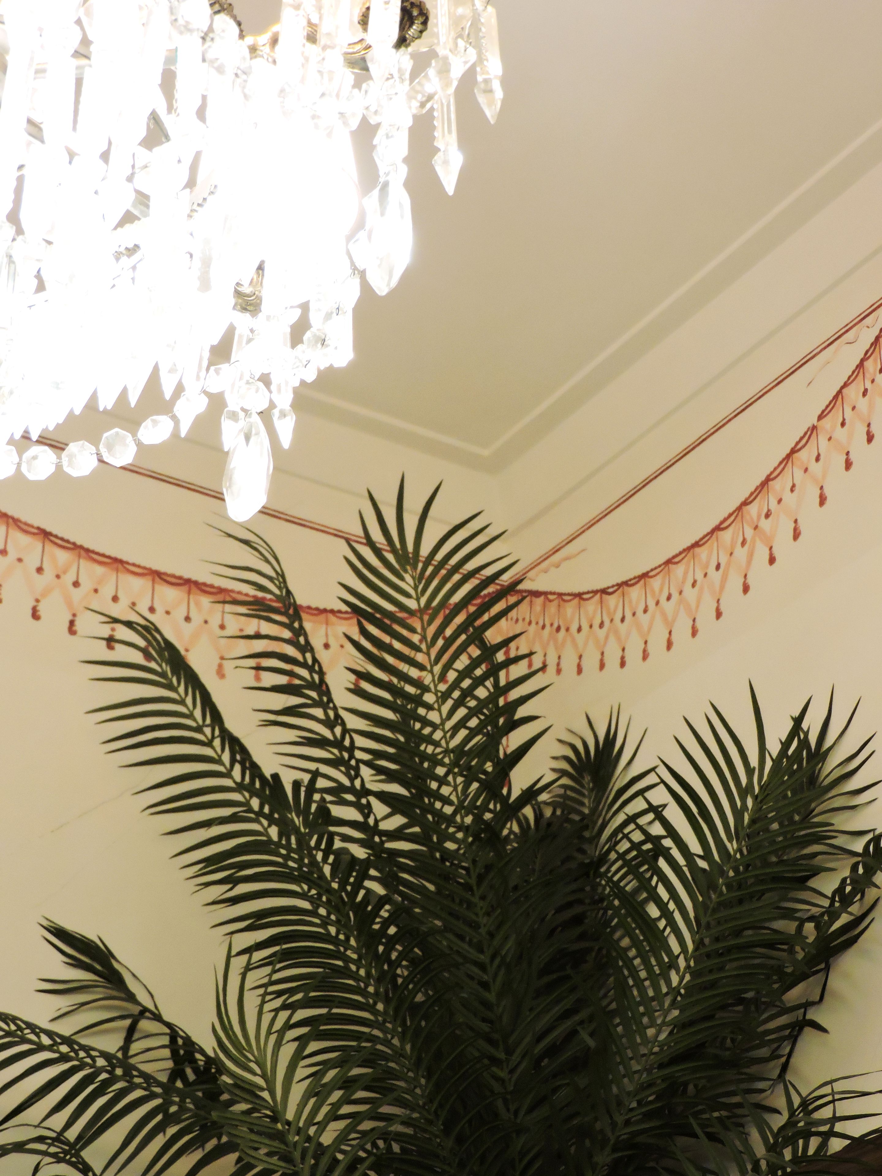 Un candelabro con adornos de cristal y una guirnalda de elementos colgantes en la pared.