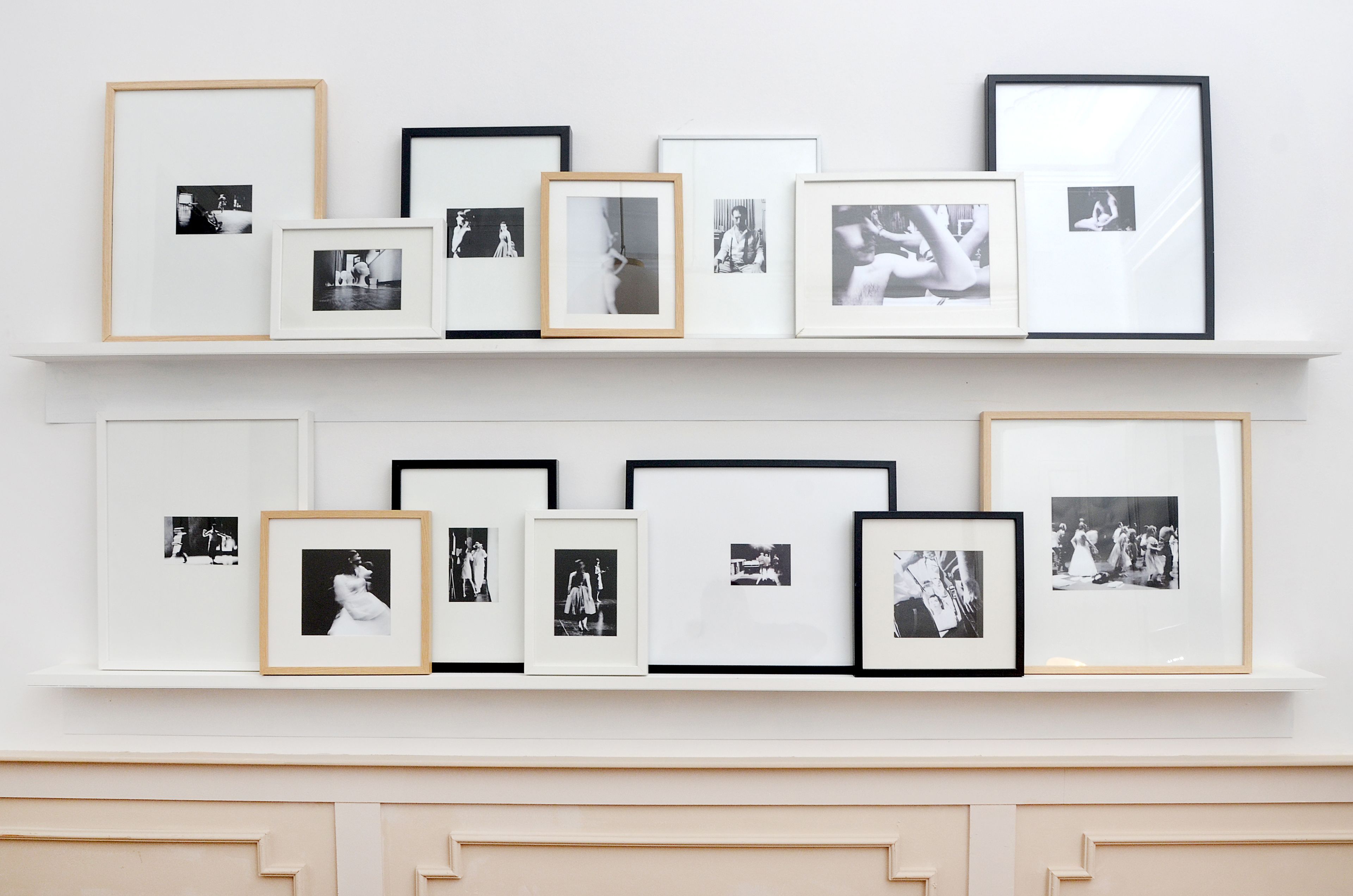 A wall with two shelves displaying framed photographs.