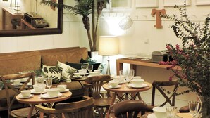 A dining area with round tables set for a meal, surrounded by wooden chairs.