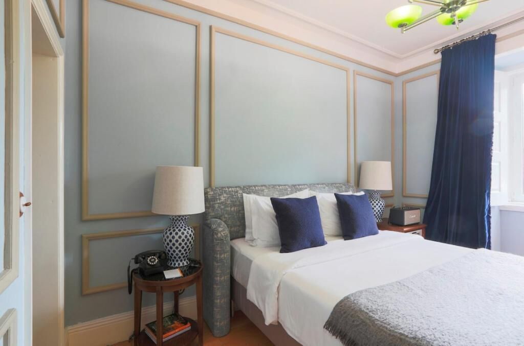A hotel room with a large bed, two bedside tables, a telephone, and a lamp.