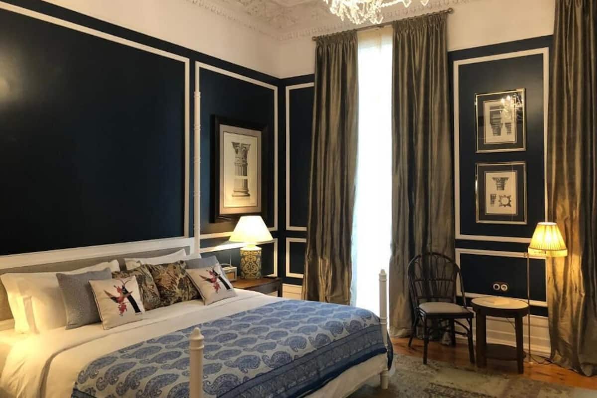A bedroom with a large bed, a nightstand, a chair, and a table.