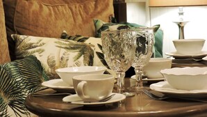 A dining table set with white dishes, two crystal glasses, and a green pillow in the background.