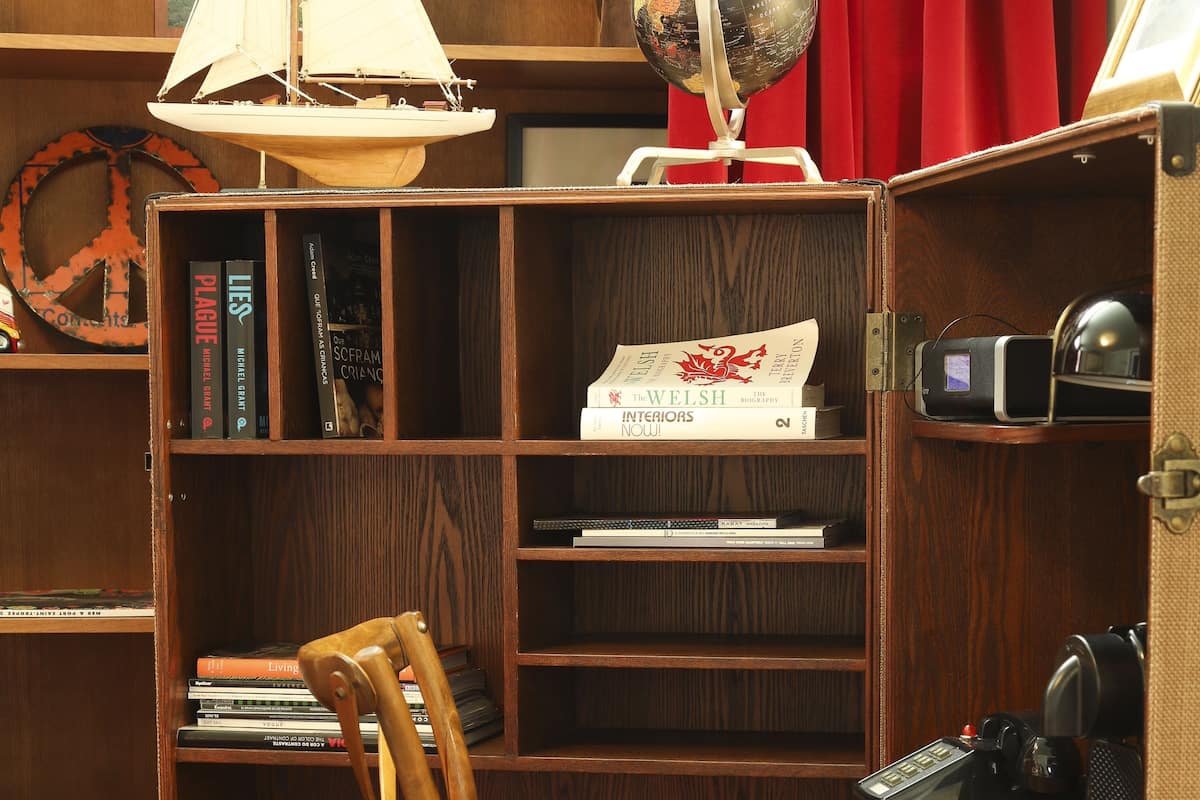 A wooden bookshelf with books, a globe, and a sailboat model.