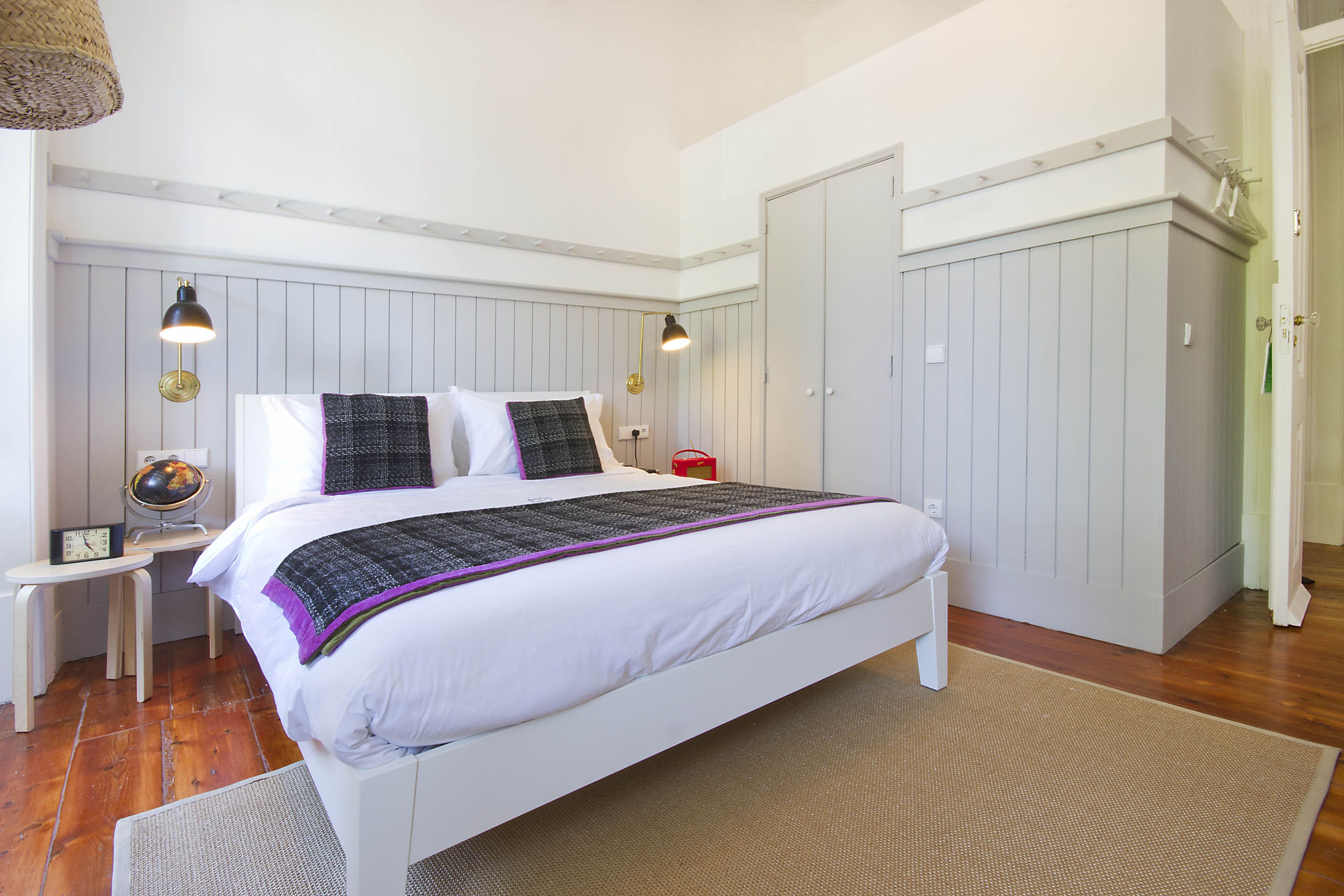 A bedroom with a bed, bedside tables, a globe, and a wardrobe.