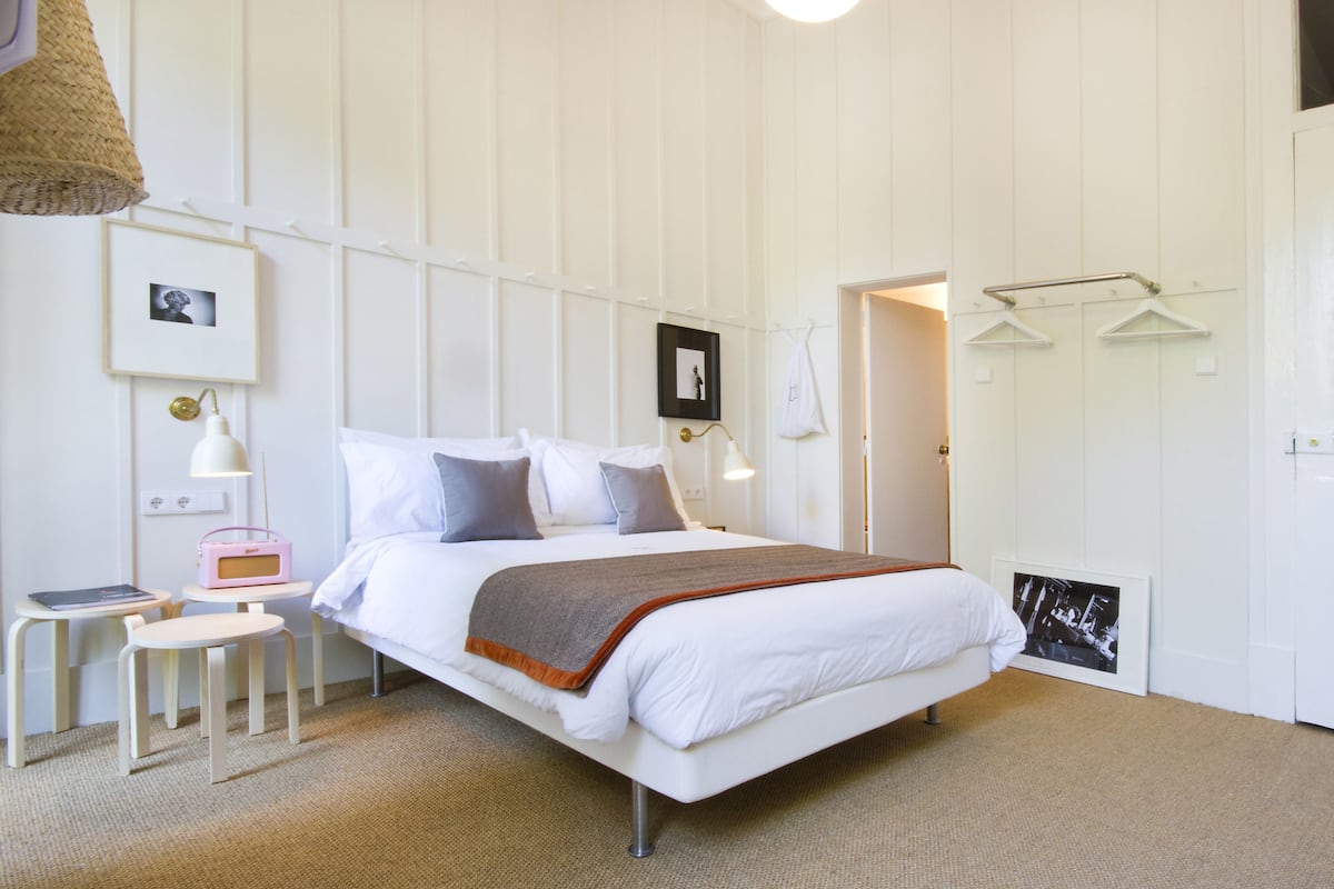 A neatly arranged bedroom with a bed, bedside tables, and a hanging light fixture.