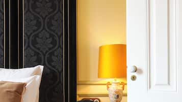A hotel room with a bed, a bedside table with a lamp, and a door.