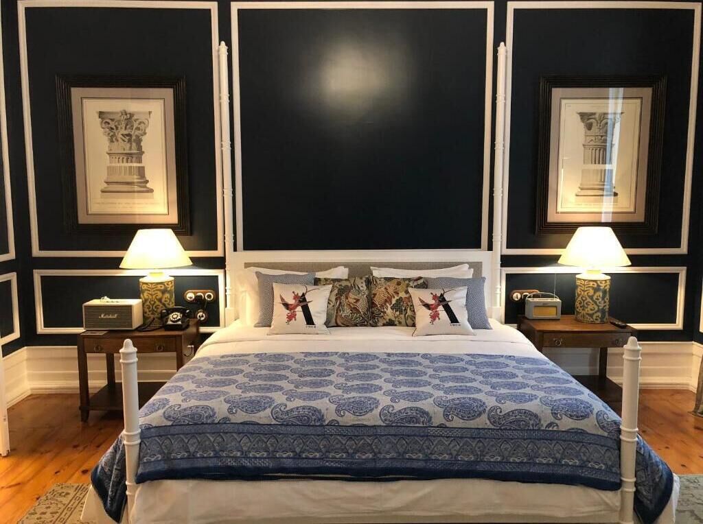 A bed with a patterned bedspread, two bedside lamps, and framed artwork on the walls.
