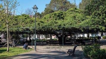 A park with benches, trees, and a covered seating area.