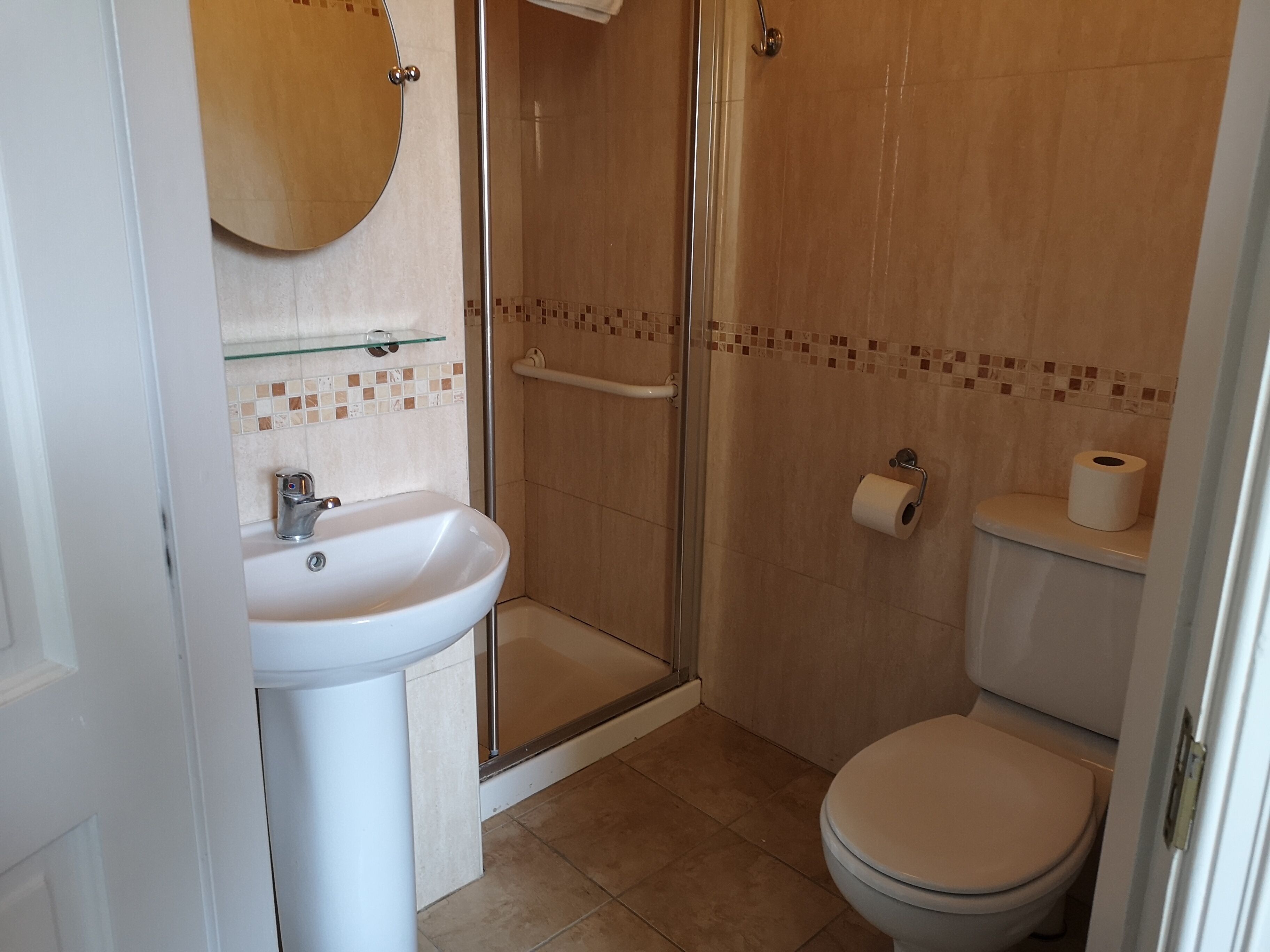 A bathroom with a white sink, glass shower enclosure, and a toilet.