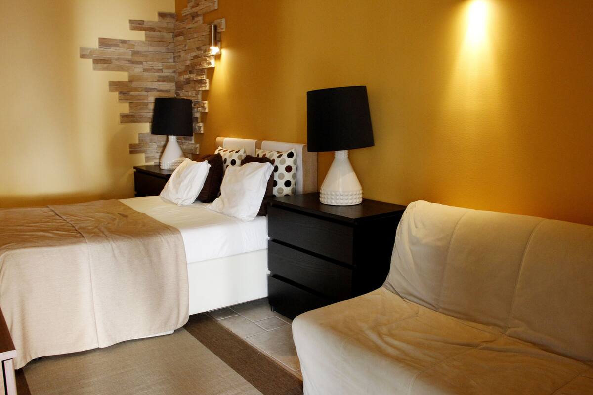 A hotel room with two beds, a black nightstand, and a white sofa.