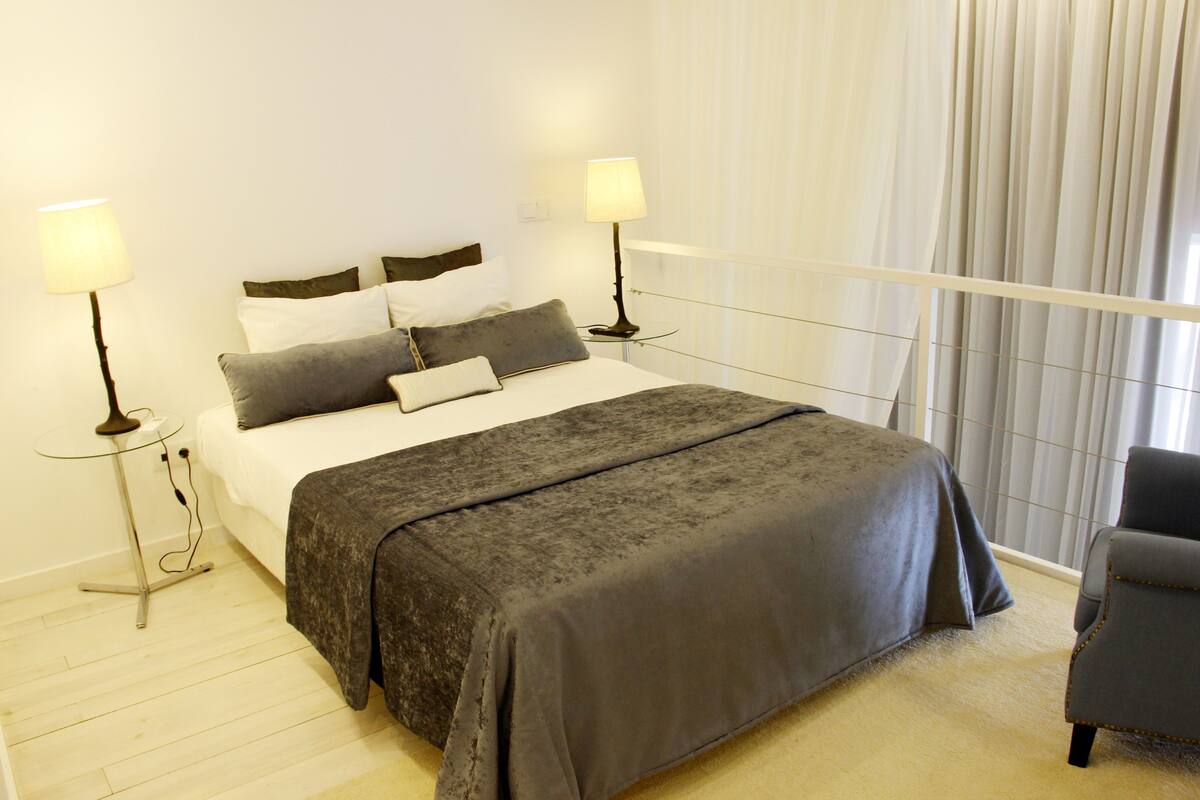 A neatly arranged hotel room with a large bed, two bedside tables, and a chair.
