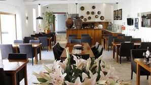 A spacious dining area with wooden tables and chairs, a central island with a bar, and a kitchen in the background. - Quinta do Molinu (Lourinha)