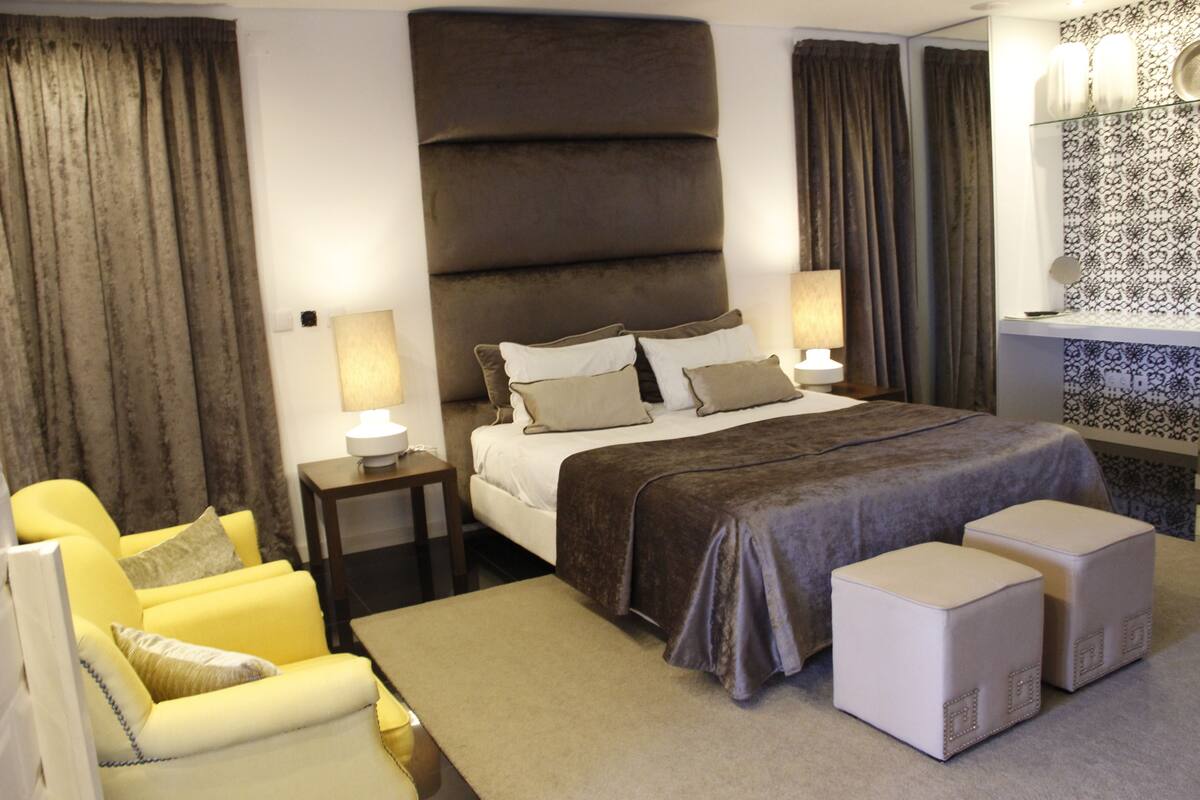 A hotel room with a large bed, two bedside tables, a chair, and a small table.