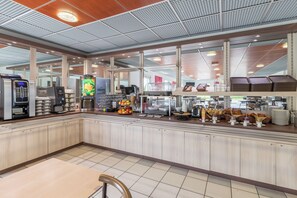A modern breakfast bar with a variety of food and drink options, including a coffee machine, fruit display, and seating area. - Ace Hôtel Roanne-Mably (Mably)