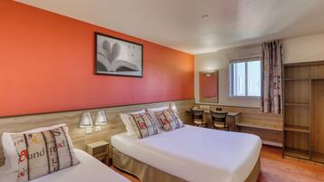 A hotel room with two beds, a desk, a chair, a wardrobe, and a window with curtains.