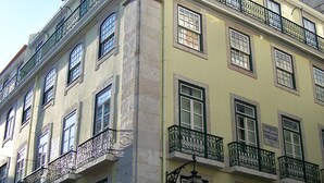 Un edificio a più piani con balconi, un'insegna che indica un'attività commerciale e un segnale di attraversamento pedonale.