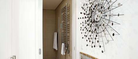 A bathroom with a shower, a towel rack, and a decorative wall piece.