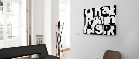 A modern living room with a sofa, a glass coffee table, and a wall-mounted artwork.