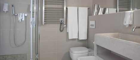 Une salle de bain moderne avec une douche à parois de verre, des toilettes, des bidet, un lavabo et un porte-serviettes.