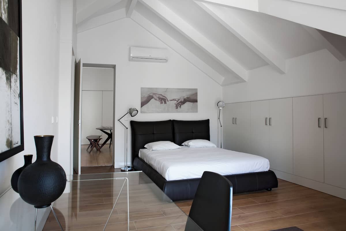 A modern bedroom with a large bed, a desk, and a chair.