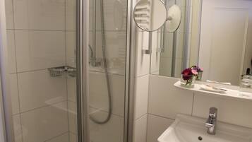 A modern bathroom with a glass-enclosed shower, a white sink, and a mirror above the sink.
