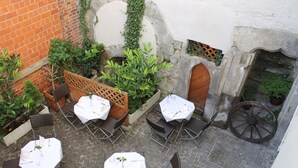 An outdoor patio area with tables and chairs, a brick wall, and a stone wall with a wooden door. - Hotel Gasthof Goldener Adler (Schwäbisch Hall)