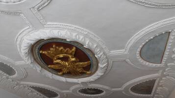 A ceiling with ornate white plasterwork and gold accents.