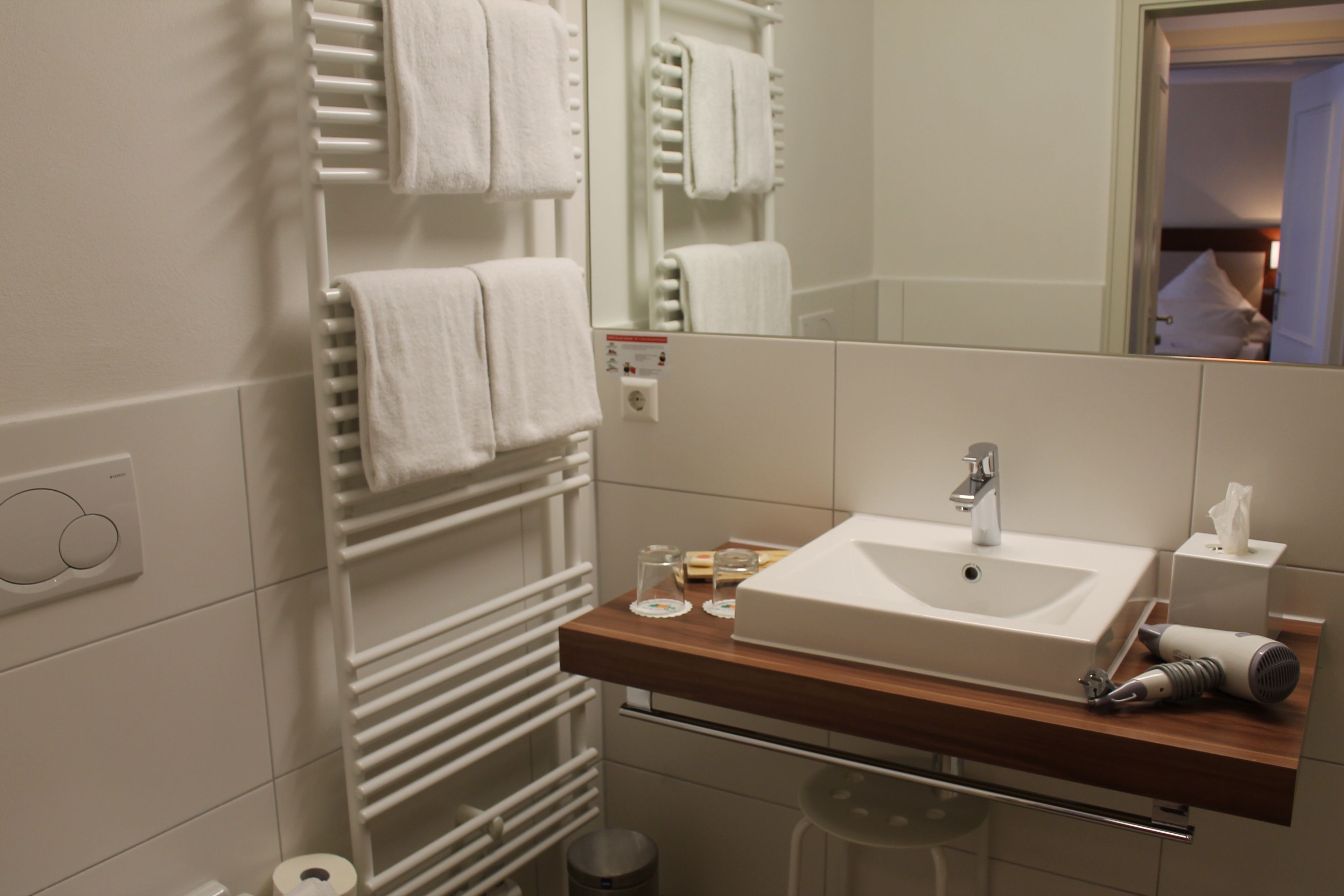 Un baño moderno con lavamanos blanco, toallero y espejo.