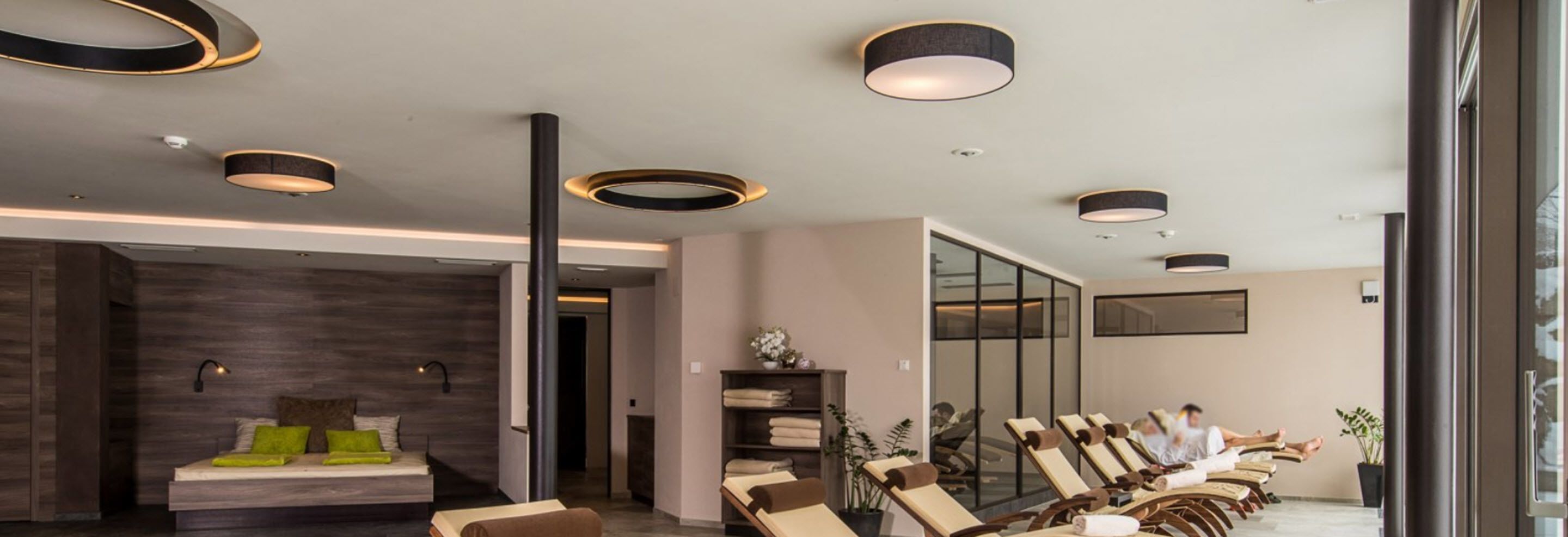 A modern spa room with a massage area, a reception desk, and a seating area with a view of the city.