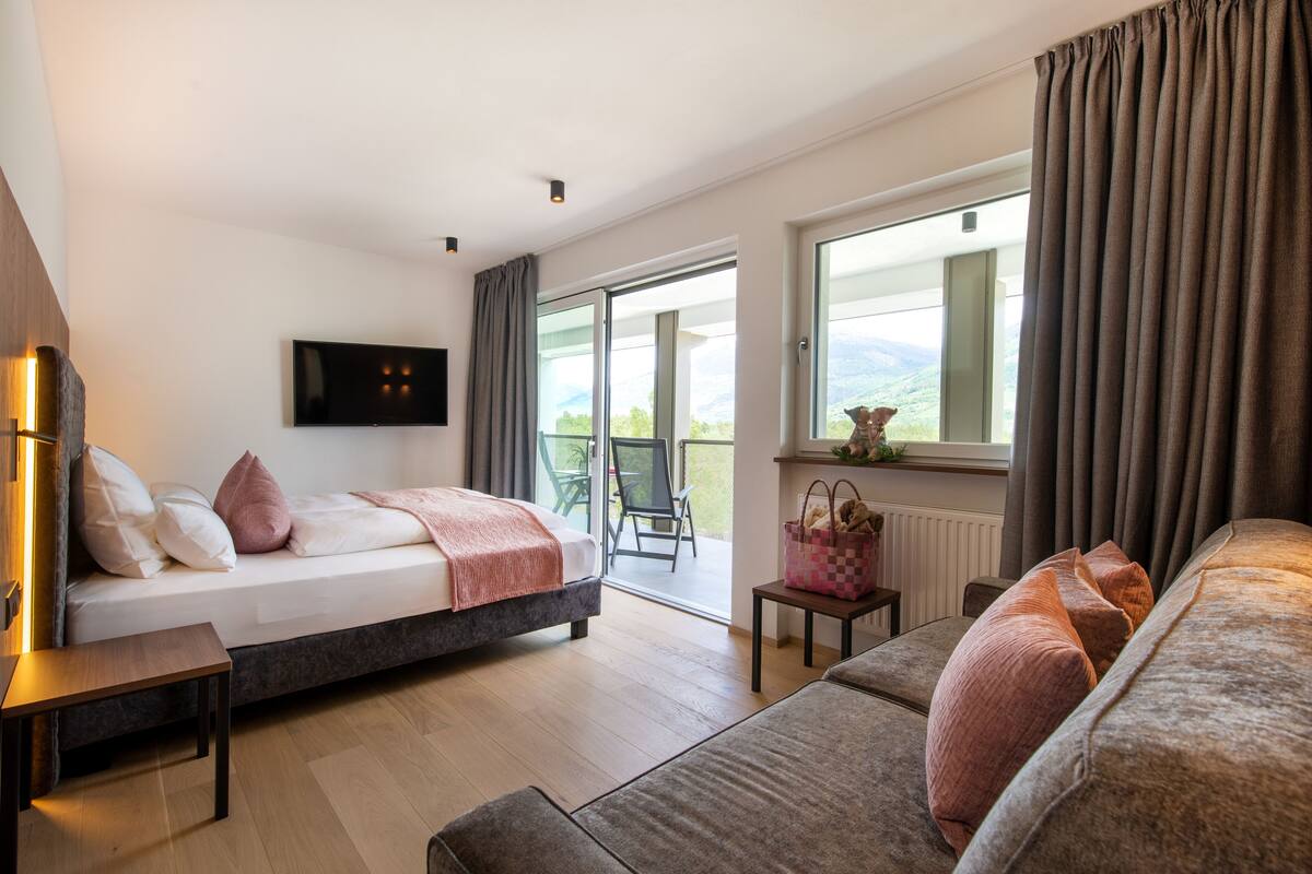 Une chambre moderne avec un lit, un canapé, une télévision et un balcon offrant une vue agréable.