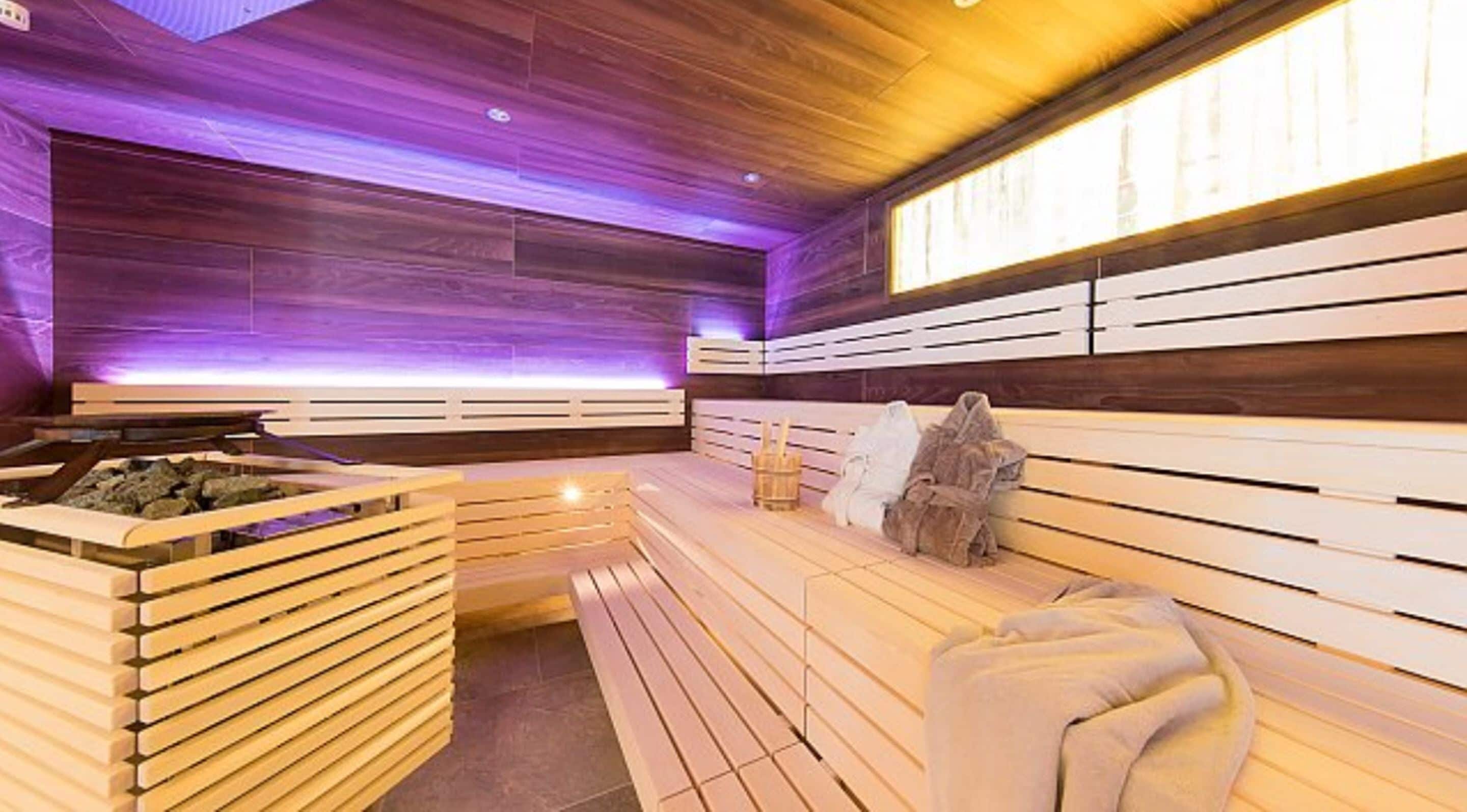 Eine Sauna mit Holzbänken und einem Steingefäß.