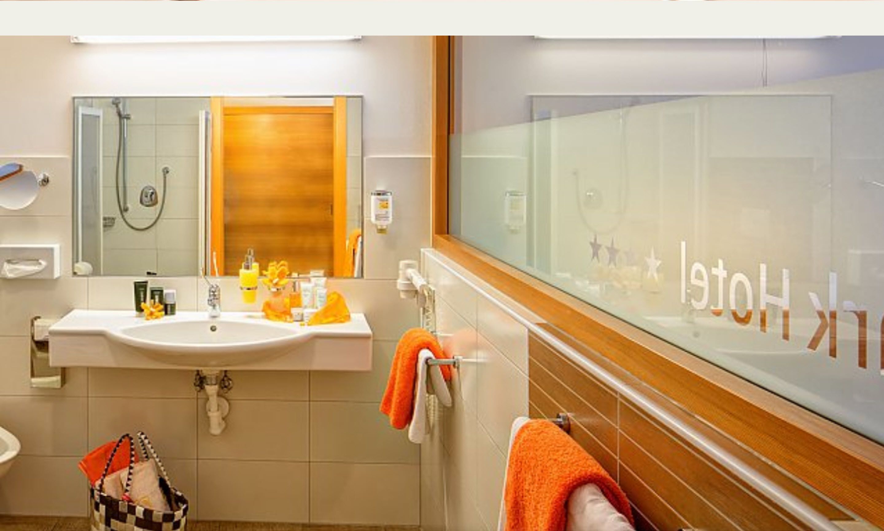 A modern bathroom with a large mirror, a sink, and a shower.