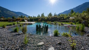 Tranquila zona de piscina al aire libre con cielo despejado, rodeada de montañas y exuberante vegetación.