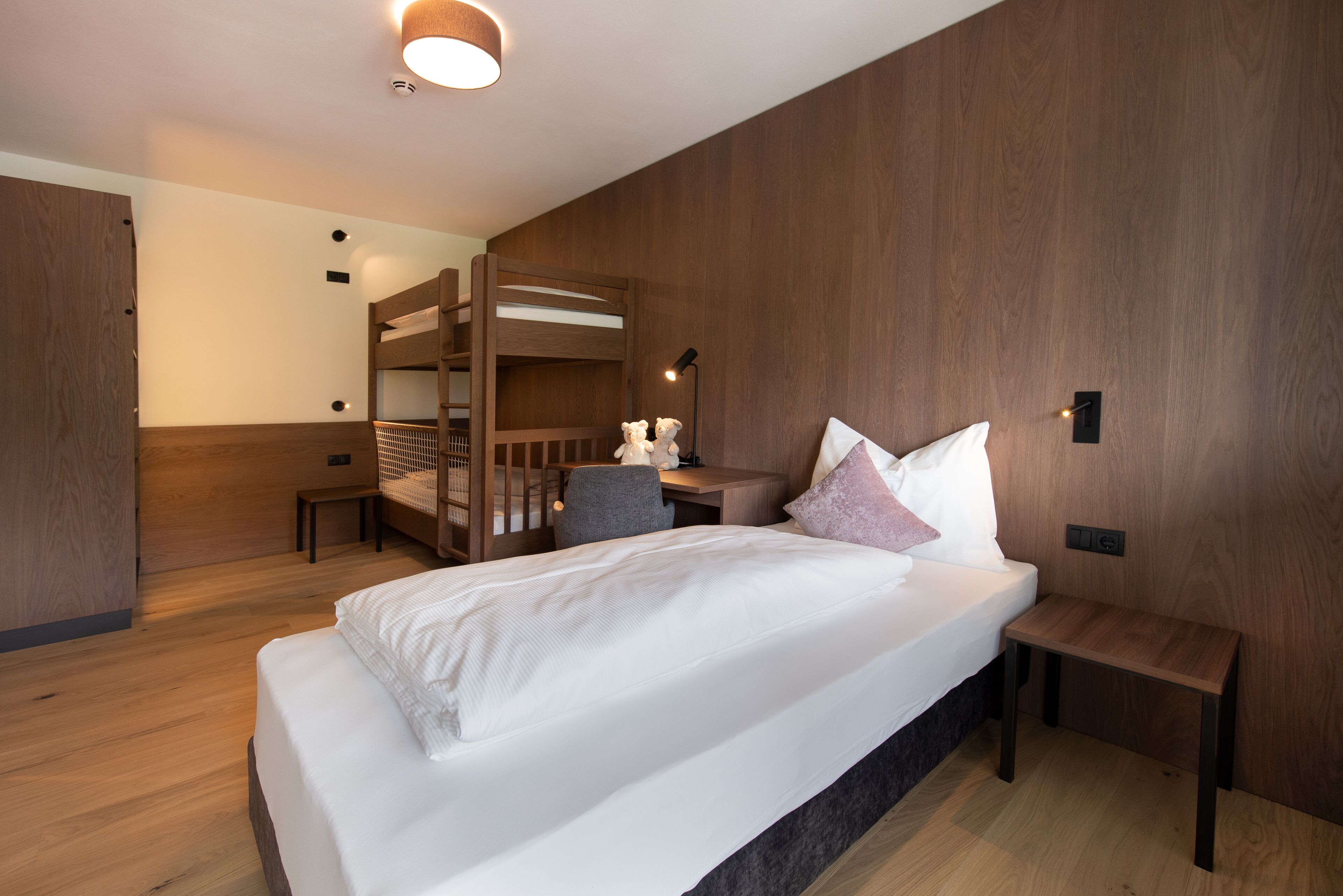 A modern bedroom with a bunk bed, a desk, and a chair.