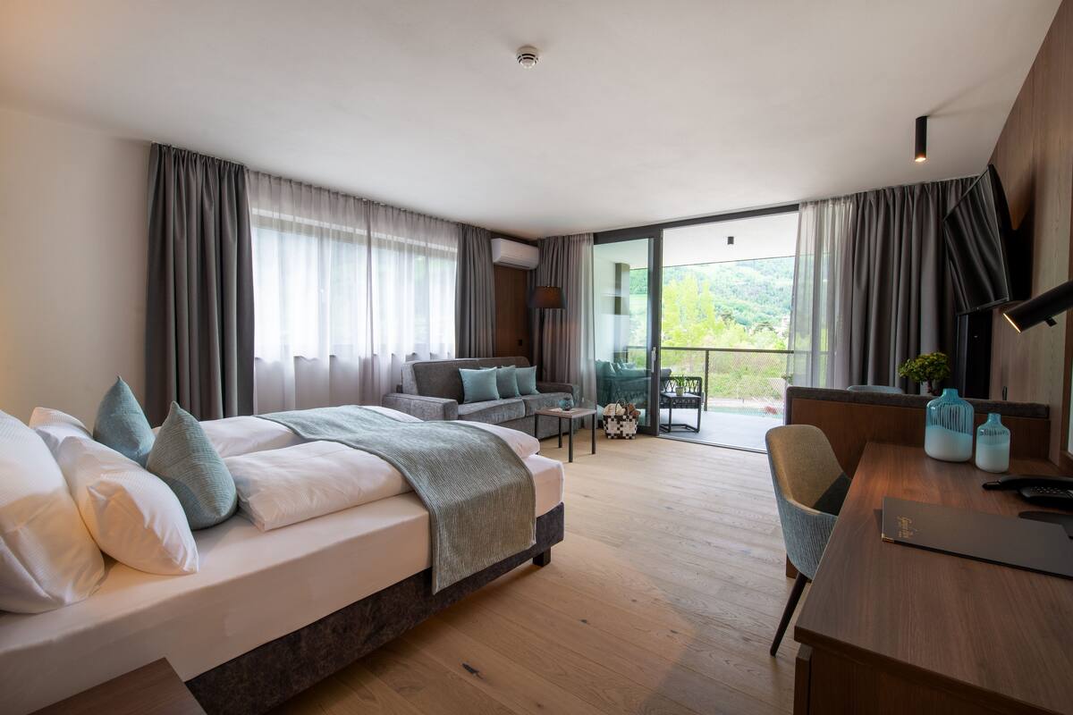 Une chambre d’hôtel moderne dotée d’un grand lit, d’un canapé, d’une table à manger et d’un balcon offrant une vue sur l’extérieur.