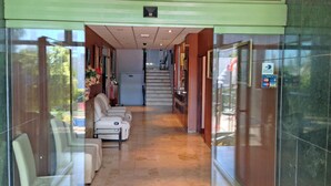 Un vestíbulo de hotel con una recepción, una escalera y un área de descanso con sillas.