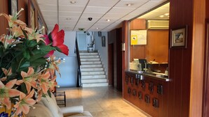 Un vestíbulo de hotel con mostrador de recepción, una escalera y una zona de estar con un arreglo floral.