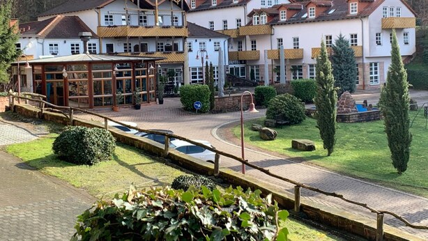 Un hotel con varios pisos, una zona de estar al aire libre cubierta y una piscina.