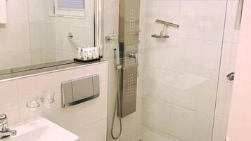 A bathroom with a glass-enclosed shower, a white sink, and a toilet.