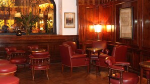 A room with wooden paneling, red leather chairs, and a large arched window with a view of the street. - Hotel Club Frances (Buenos Aires)