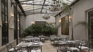 An indoor dining area with tables and chairs, a chandelier, and potted plants. - Hotel Club Frances (Buenos Aires)