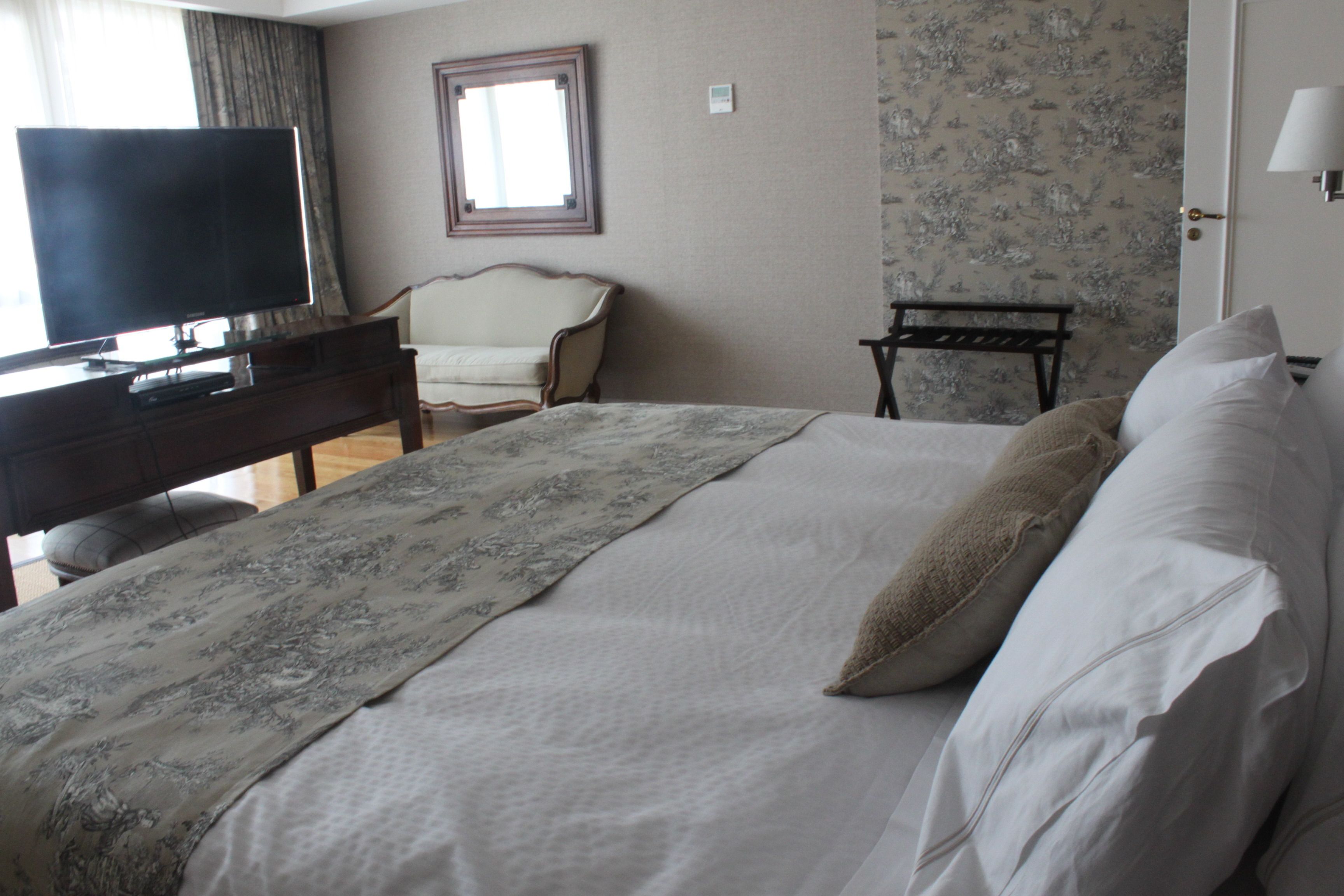 A hotel room with a bed, a television, a chair, and a desk.