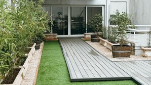 A modern outdoor patio with artificial grass, wooden decking, and potted plants. - Hotel Club Frances (Buenos Aires)
