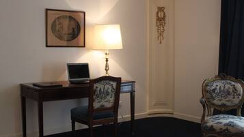 Une pièce comprenant un bureau, un ordinateur portable, une lampe, une chaise et un tableau encadré accroché au mur.