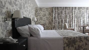 A hotel room with a bed, two bedside lamps, a telephone, a chair, and a table.
