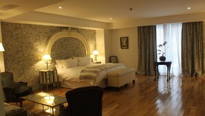 A hotel room with a large bed, two bedside tables with lamps, a small table with a chair, a chair, and a large window with curtains. - Hotel Club Frances (Buenos Aires)