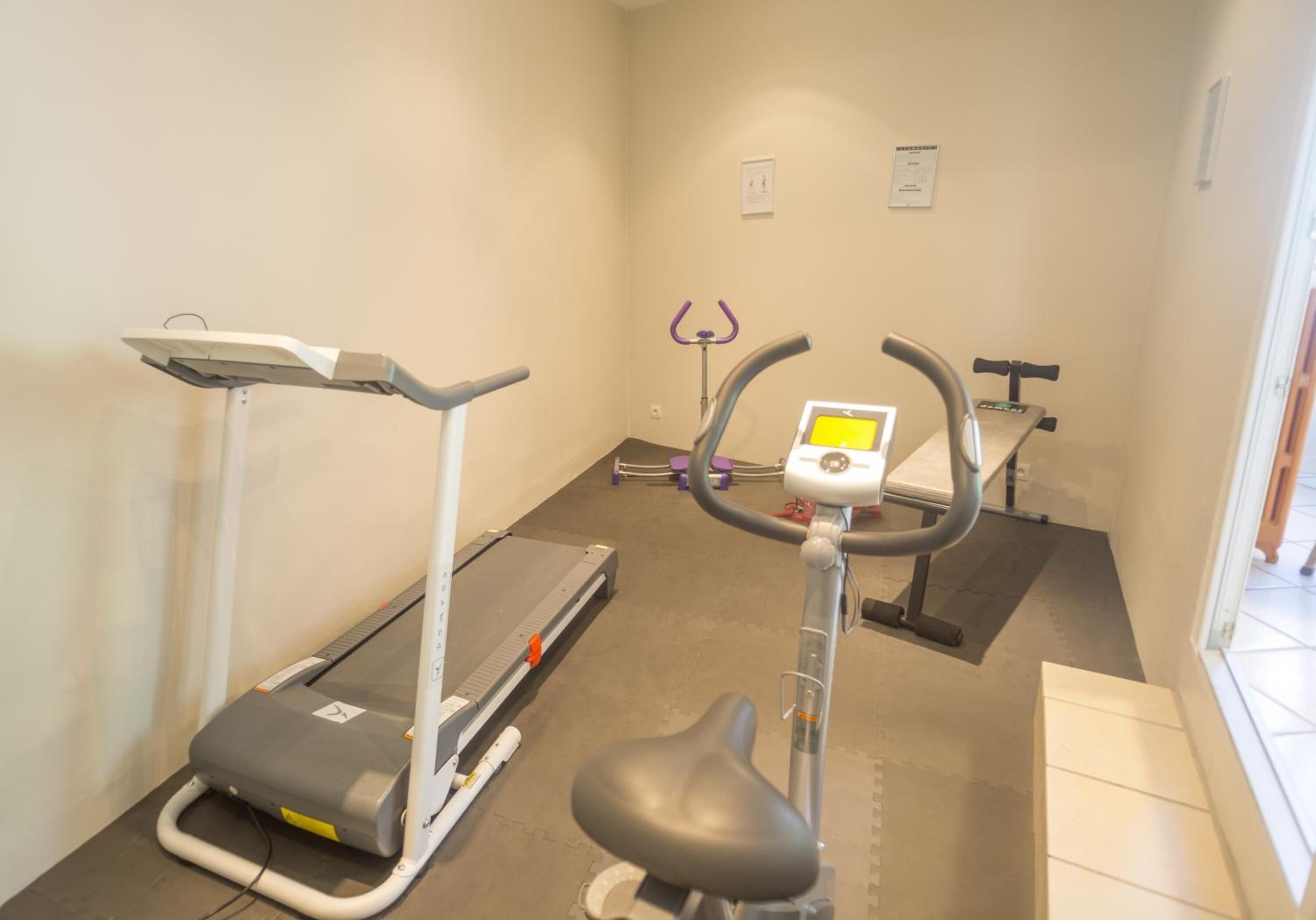 A small gym with a treadmill, elliptical, and stationary bike.