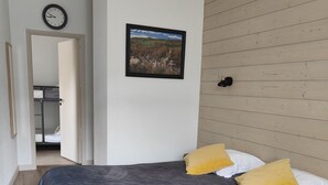 Een slaapkamer met een bed, een houten wandpaneel, een ingelijste foto en een klok aan de muur.