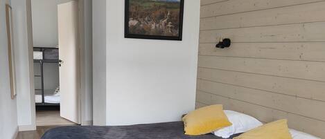 Un dormitorio con cama, panel de madera, un cuadro enmarcado y un reloj en la pared.