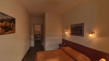 Een hotelkamer met een bed, een nachtkastje, een wandlamp en een schilderij aan de muur.